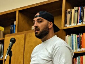 Color photo of Tamer Mostafa standing at microphone