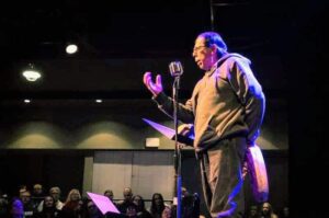 image of Monolin "Manny" Moreno at a reading with dark background